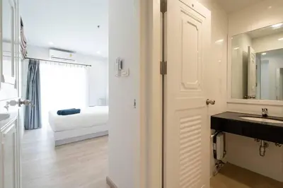 a white bathroom with a sink and a bedroom at Brand New Patong Apartment 1-Bedroom in Patong Beach