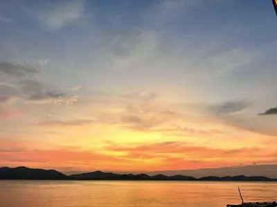 a sunset over a body of water with a boat at บ้านสวนปิยนันท์ (Baansuan Piyanan) in Ko Yao Noi