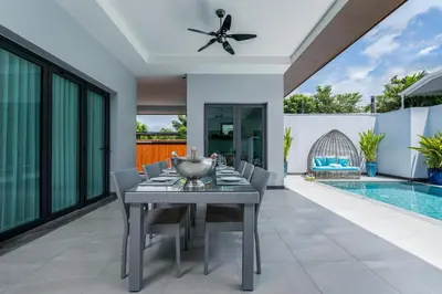 a dining room with a table and chairs and a pool at Two Flamingo Villa 1 in Ban Pak Lak