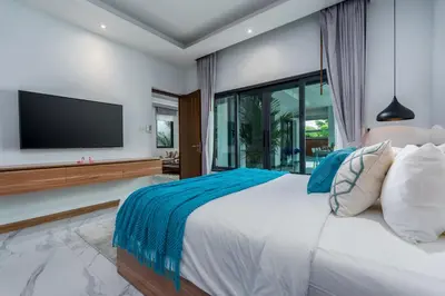 a bedroom with a large bed and a flat screen tv at Two Flamingo Villa 1 in Ban Pak Lak