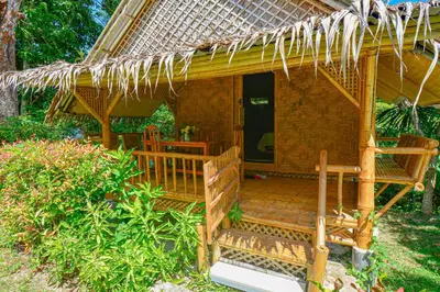 a hut with a deck with a thatched roof at Ratanaporn Green in Phuket Town