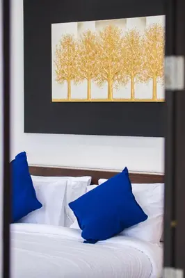 a bed with blue pillows and a picture of trees at Mango Hill Residence in Rawai Beach