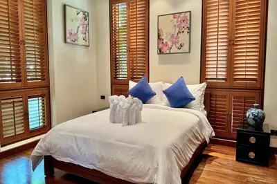 a bedroom with a white bed with blue pillows at Seaview 5BR Pool Villa Apsara, Free Breakfast and Full Service, 5 min walk to Kata Beach in Kata Beach
