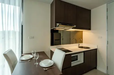a kitchen with a table with chairs and a sink at Aristo 1 Apartments by Beringela in Surin Beach