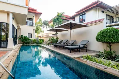a swimming pool in a villa with chairs and an umbrella at Grand 4-Bed Lagoon Villa - Private Pool & Garden - Laguna in Ban Thalat Choeng Thale