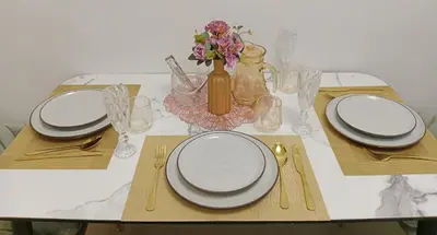 a table with plates and glasses and a vase with flowers at STP apartment 3rd floor in Patong Beach