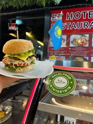 a person holding a sandwich in front of a counter at BT hotel Kata Beach in Kata Beach