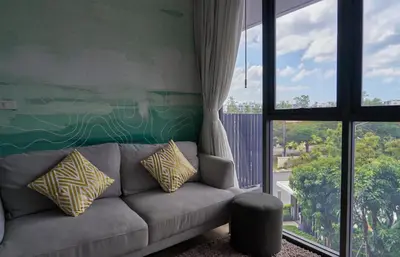 a living room with a couch and a large window at Modern 2-bedroom Apartments with washer in Skypark Laguna Bang Tao in Phuket Town