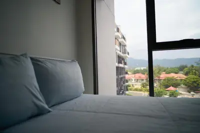 a bed in a room with a view of a building at Modern 2-bedroom Apartments. Skypark Laguna (Bang Tao) in Bang Tao Beach