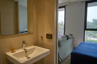 a bathroom with a sink and a bed and a mirror at Cozy 1-bedroom Apartments in Laguna Skypark Bang Tao in Phuket Town