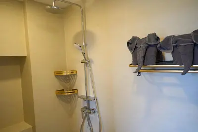 a bathroom with a shower and towels on a shelf at Cozy 1-bedroom Apartments in Laguna Skypark Bang Tao in Phuket Town