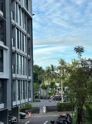 a woman is standing next to a building with motorcycles at Cassia Residences in Phuket Town