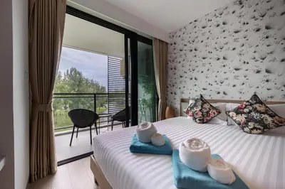a bedroom with a bed and a large window at Cassia 2 BR Sea View apt by NLA in Phuket Town