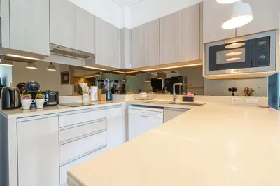 a kitchen with white cabinets and a counter top at Cassia 2 BR Sea View apt by NLA in Phuket Town