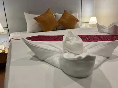 a white flower sitting on a white bed at Zephyr Grand Hotel in Patong Beach