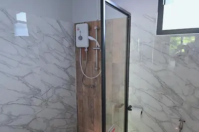 a shower in a bathroom with white marble walls at Aonangstudio in Krabi town