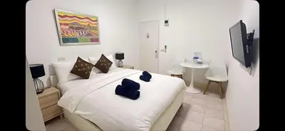 a bedroom with a white bed with blue pillows on it at Elephant Sports Bar and Accommodation in Phuket Town