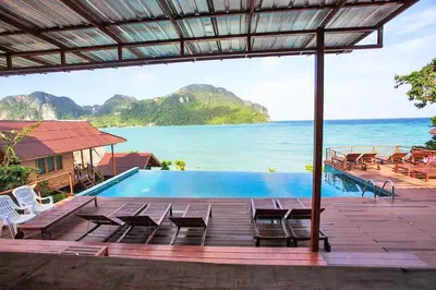a pool with chairs and a view of the ocean at The Cobble Beach Hotel- Phi Phi Island in Phi Phi Don