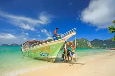 a group of people standing on a boat on the beach at The Cobble Beach Hotel- Phi Phi Island in Phi Phi Don
