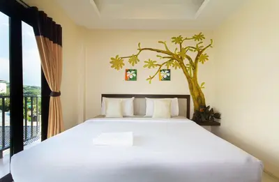 a bedroom with a bed with a tree on the wall at KRABI MORE HOTEL in Klong Muang Beach