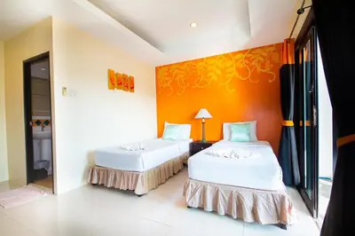 two beds in a room with an orange wall at KRABI MORE HOTEL in Klong Muang Beach