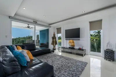 a living room with a black leather couch and a tv at The Blue Bay Experience in Kata Beach