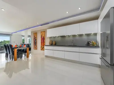 a kitchen with white cabinets and a table with chairs at The Blue Bay Experience in Kata Beach