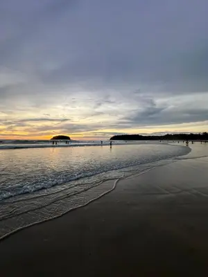 a beach with the ocean and a pier in the distance at BT hotel Kata Beach in Kata Beach