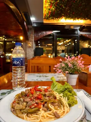 a plate of pasta and a bottle of water on a table at BT hotel Kata Beach in Kata Beach