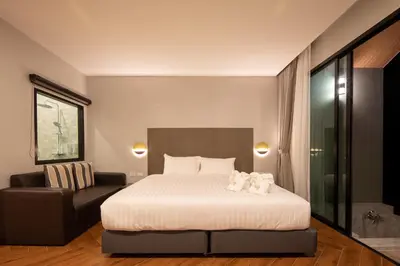 a hotel room with a bed and a chair at Nature Vista Rawai in Nai Harn Beach