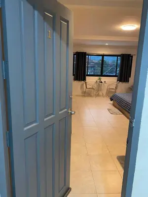 a hallway with a blue door and a room with a couch at 84 Bar & Guest House in Ban Huai Luk (1)