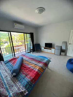 a bedroom with a large bed and a balcony at Petunya Room 3 in Ban Huai Luk (1)