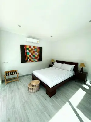 a bedroom with a bed and a painting on the wall at A spacious Balinese style villa with a large swimming pool on Rawai an electric motorcycle as a gift! in Ban Saiyuan (1)