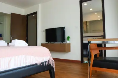 a bedroom with a bed and a tv on a wall at Friendly Townhouse Laguna Park in Thalang