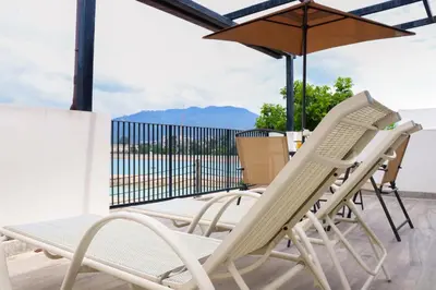 two chairs and an umbrella on a patio at Friendly Townhouse Laguna Park in Thalang