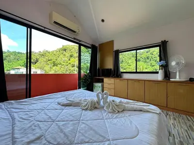 a bedroom with a bed with two white towels on it at Coco Mountain View Guest House Hotel in Kata Beach