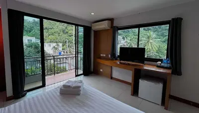 a room with a desk with a computer and large windows at Coco Mountain View Guest House Hotel in Kata Beach