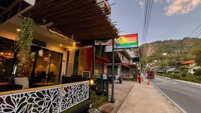a building on the side of a street with a sign at Coco Mountain View Guest House Hotel in Kata Beach