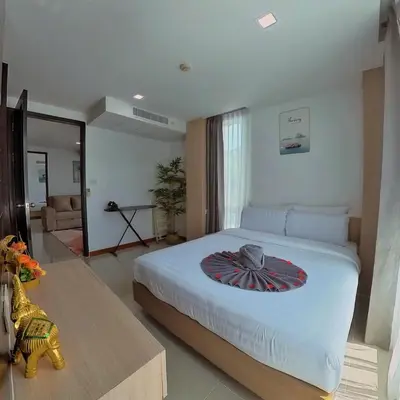 a bedroom with a large bed and a living room at The Kris 2 Bedrooms 2 Bathrooms Apartment in Patong Beach