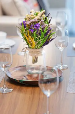 a vase of flowers on a table with wine glasses at Reach Patong beach in one minute in Patong Beach