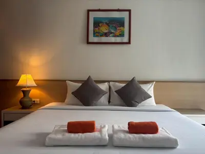 a bedroom with a white bed with two towels at Priew Wan Guesthouse in Patong Beach