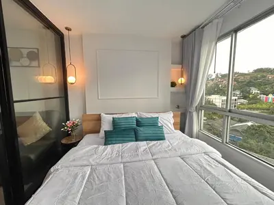 a bedroom with a bed with blue pillows and a window at Vibe Old Town 452 in Phuket Town