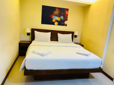 a bedroom with a large bed with white sheets at Patong Terrace Hotel in Patong Beach
