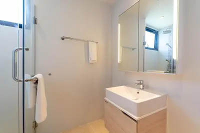 a white bathroom with a sink and a mirror at Bangtao Beach Apartments in Bang Tao Beach