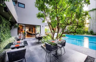 an outdoor dining area with tables and chairs and a pool at Bangtao Beach Apartments in Bang Tao Beach