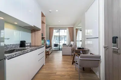 a kitchen with white cabinets and a table in a room at Bangtao Beach Apartments in Bang Tao Beach