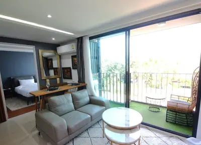 a living room with a couch and a balcony at The Aristo 1 Condo Surin Beach in Phuket Town