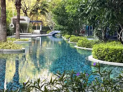 a swimming pool in a resort with trees and water at The Aristo 1 Condo Surin Beach in Phuket Town