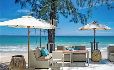 a table and chairs and umbrellas on the beach at The Aristo 1 Condo Surin Beach in Phuket Town