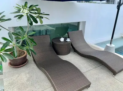 two wicker chairs sitting on a balcony with plants at The Regent Kamala Penthouse with private pool in Kamala Beach